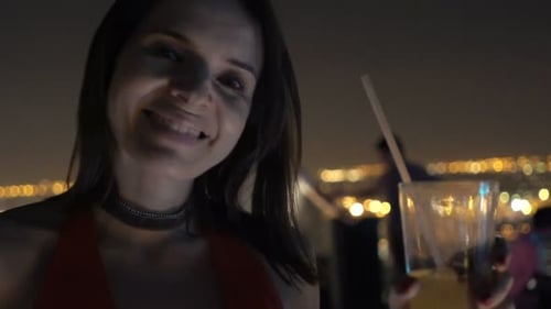 Elegant woman enjoys a cocktail on a luxurious rooftop terrace at night