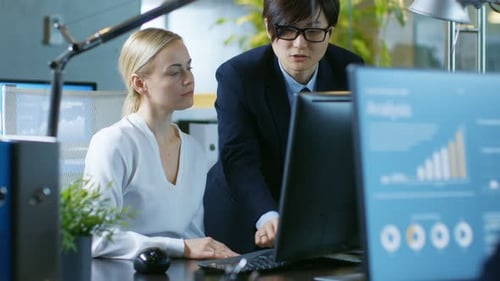 Im Büro spricht eine junge Geschäftsfrau, die an ihrem Schreibtisch sitzt, mit ihrem Manager, sie zeigen auf C