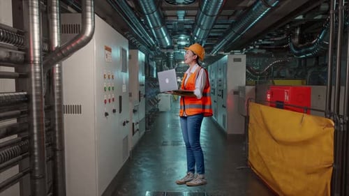Full Body Side View Of Asian Female Engineer Working On A Laptop In Engine Control Room