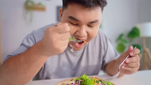Man Eats Healthy Salad at Table Inside