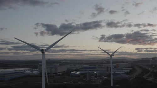 Two wind power generators around the city at dawn.