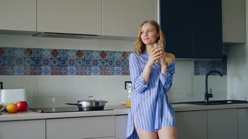 Young woman drinks orange juice in kitchen setting
