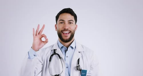Man, face and ok sign of doctor in studio for success, healthcare feedback