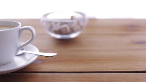 Cream pouring into a hot coffee cup on a wooden table breakfast concept