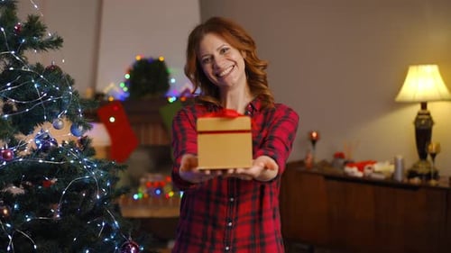 Woman Holding Christmas Gift with Festive Background