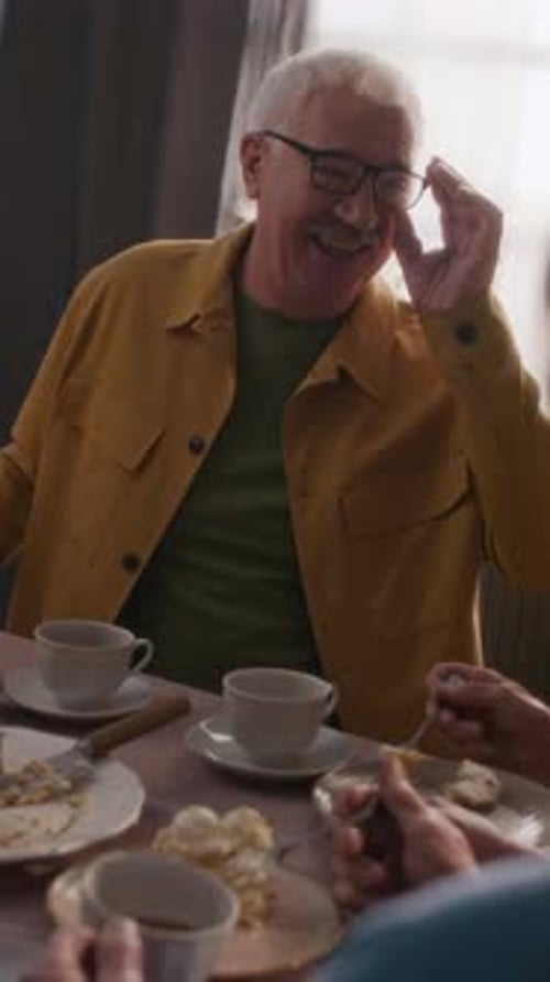 Senior Man Chatting at Table with Dessert and Tea