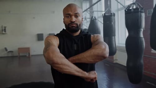 Afroamerikaner mit ernstem Gesichtsausdruck verschränkt die Arme im Fitnessstudio