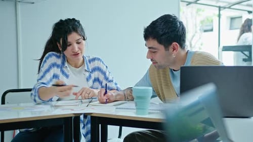 Jeunes collègues prenant des notes et discutant d'idées commerciales au bureau