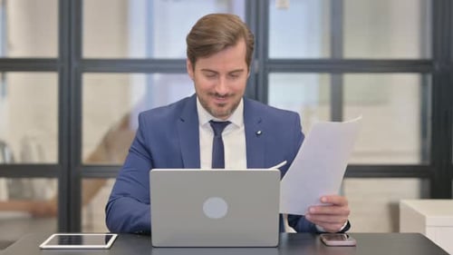 Businessman Celebrates Success at Office Desk