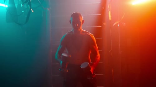 Muscular Man Lifting Dumbbells in a Dark Gym