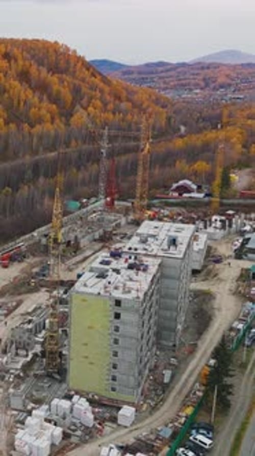 Construction of a Multistory Building in Autumn Surrounded By Vibrant Trees and Mountains