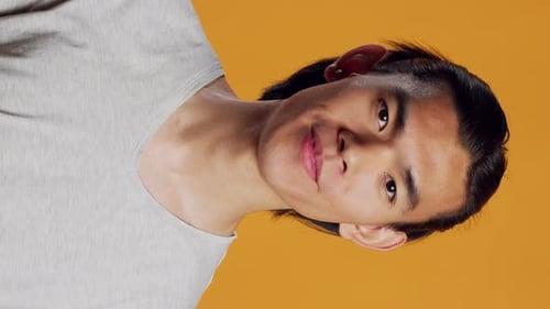 Vídeo vertical, alegre, sorridente, posando em fundo laranja