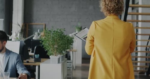 Back View of Young Businesswoman Walking in Office Meeting Colleagues Then Working with Computer