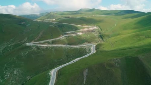 Aerial Over Winding Asphalt Road Among Mountains Covered with Green Grass in Highlands of Caucasus