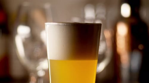 Craft Beer being poured in to a pint glass, light background, close up