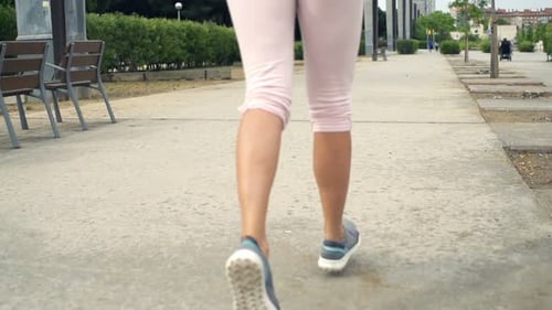 Young woman jogging through the city streets in super slow motion