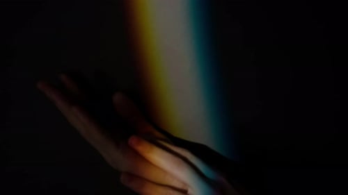Hands in Darkness Bathed in Rainbow Light