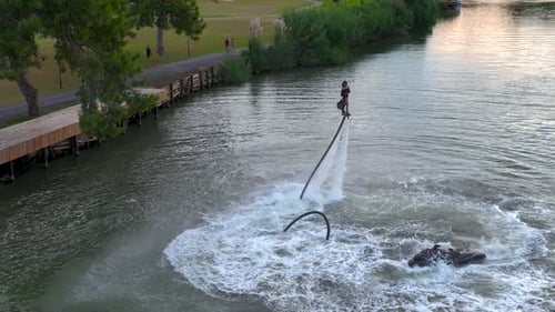 Aerial View Bold Lady Flyboarding Across River at Twilight