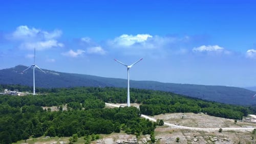 View Of Wind Turbines Spinning On Top Of A Mountain. generating clean renewable energy . 4K. blue sk