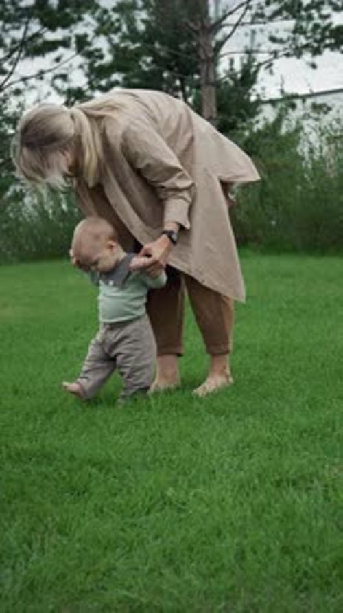 Young Mother Teaching Her Son To Walk