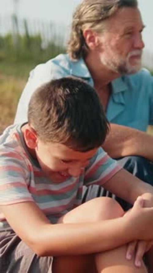 Grandfather and Grandson Sitting and Talking Outside
