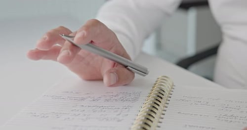 Nahaufnahme von Händen Ein Mann in einem Hemd hält einen Stift in der Hand und trommelt seine Finger auf einem Notizblock auf einem