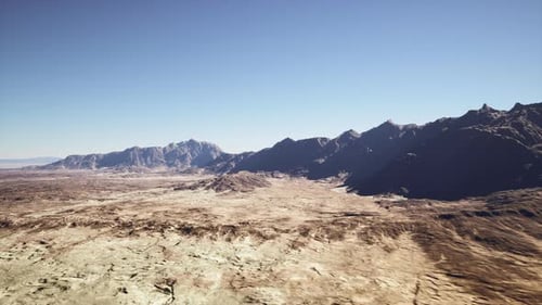 Vast Dry Valley Under Clear Sky with Mountain Range and Textures