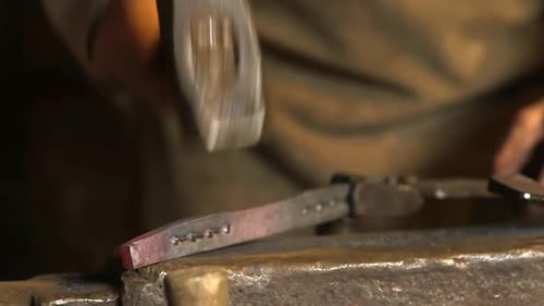 Blacksmith Shaping Hot Metal with Hammer on Anvil