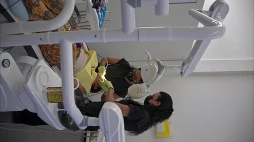 Vertical dolly out shot in slow motion of a female dentist and her assistant dressed in black wearin