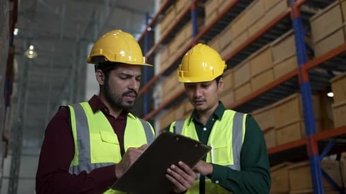 Blue collar workers are working at warehouse.