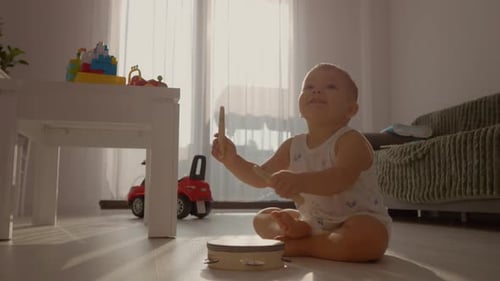 Child Plays Tambourine with Drumsticks at Home