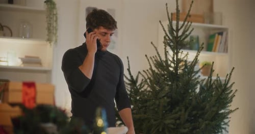 Man Talking on Phone Near Christmas Tree