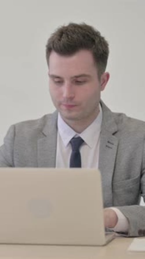 Young Businessman Celebrating Online Success on Laptop in Office, vertical video