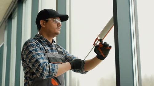 Man Caulking Office Window Frame