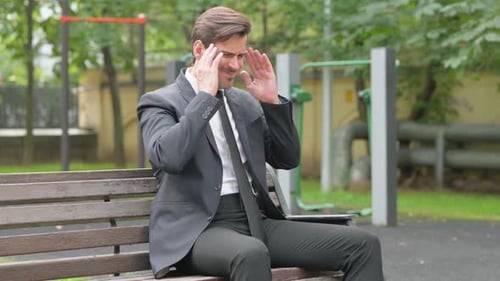 Tense Businessman with Migraine Sitting Outdoor