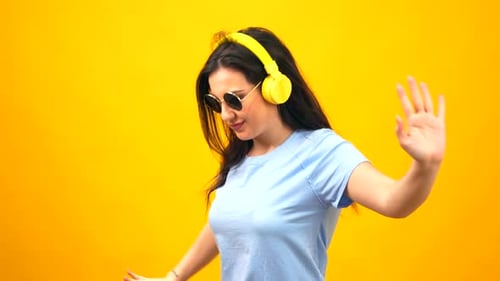 Happy woman dancing wearing sunglasses and headphones on the neck