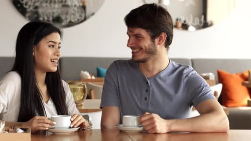 Young Man Enjoys a Lively Conversation with His Female Friend at a Trendy Cafe