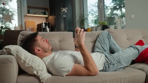 Man Lies on Couch Using Mobile Phone