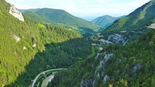 Eine kurvenreiche Straße führt durch Bergschluchten mit Pflanzen mit Laub unter einem Tageshimmel in Rhodopen