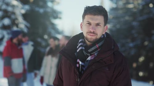 Man in Winter Coat with Friends in Snowy Park