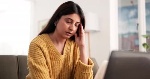 Worried Woman Sitting on Sofa Using Laptop