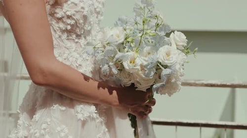 Bride holds her wedding bouquet on sunny day
