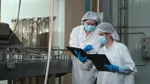 Deux superviseurs féminins inspectent le processus de production sur le convoyeur d'une usine alimentaire.