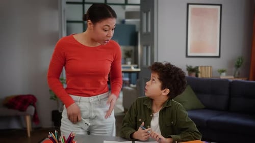 Boy Doing Homework as Woman Talks Nearby
