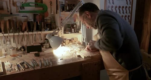 Luthier violin maker artisan carving woodwith gouge for crafting violin belly in workshop