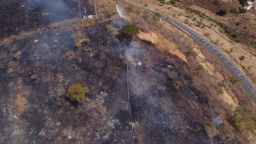 Helicopter extinguishing burn damaged smoky hillside aerial view overlooking town natural disaster