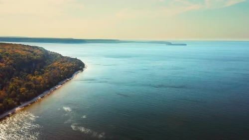 Península da floresta de outono que se estende até o calmo lago azul — Vista aérea
