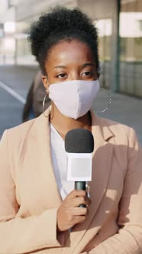 Woman Reporter Wearing Mask Holding Microphone Outside