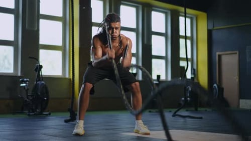 Intense Man Working Out With Ropes in Gym