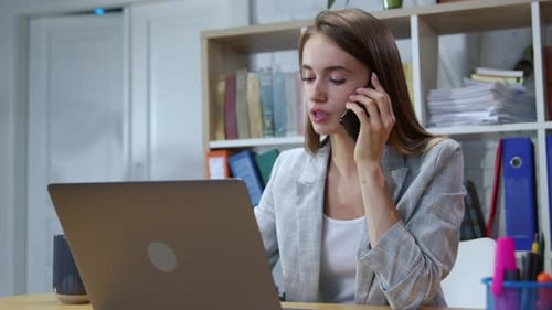 Woman Works at Laptop and Talks on Cell Phone